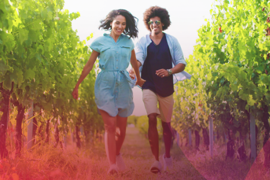 2 people walking through a vineyard smiling.